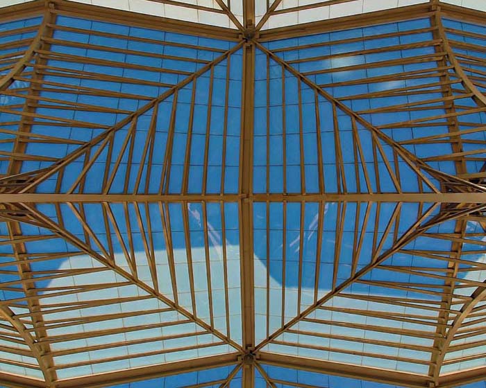 Stock image of a decorative pattern in wood on a ceiling with a blue sky visible between panels 