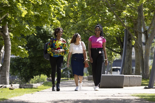 Three students walking together on campus in the sunshine