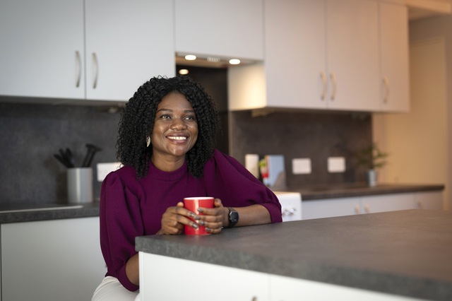 A student with a mug in a kitchen