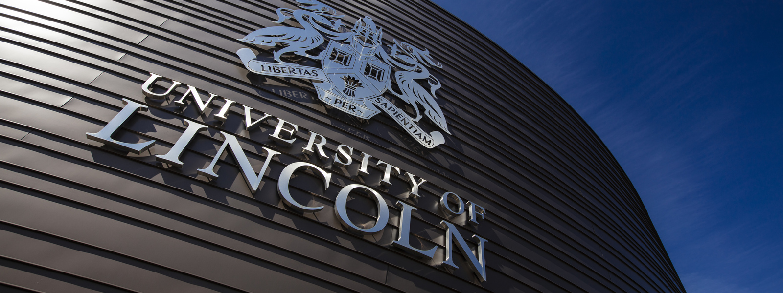 An exterior image of the Isaac Newton Building and University of Lincoln crest