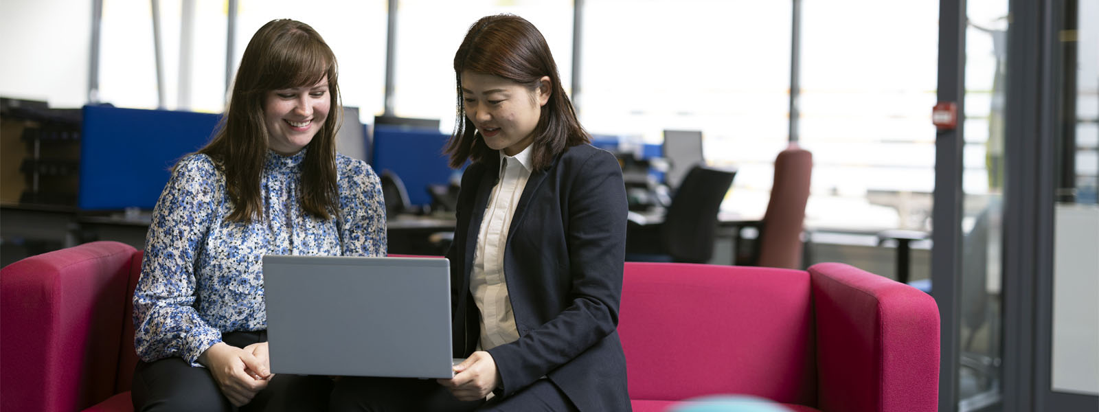 Two students sat working on a laptop