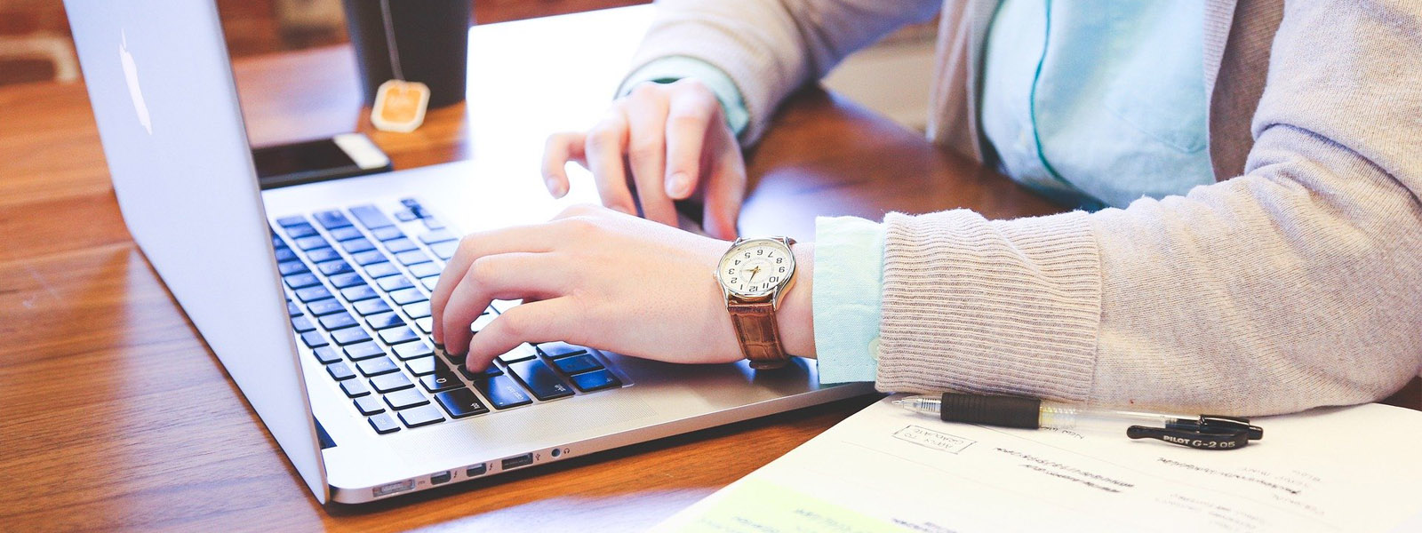 A student working on a laptop with books on a desk