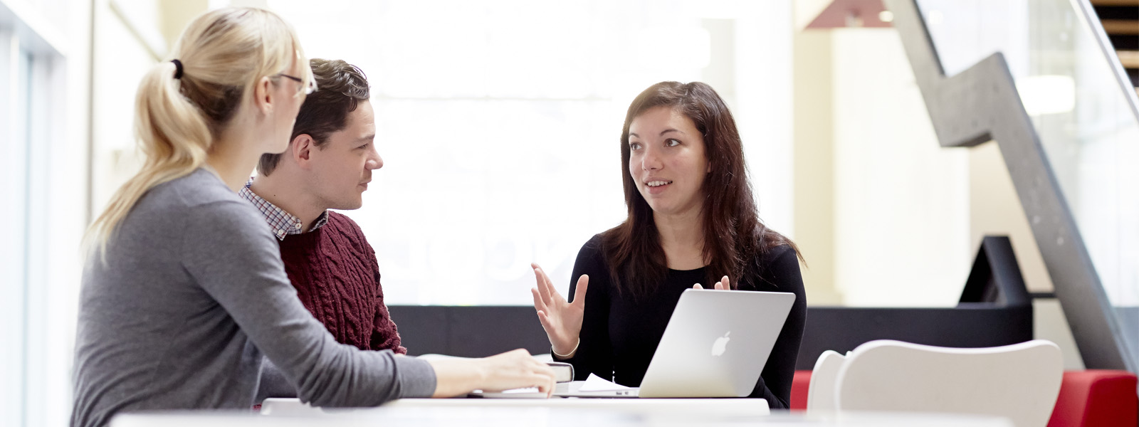 Three students in conversation in a teaching room