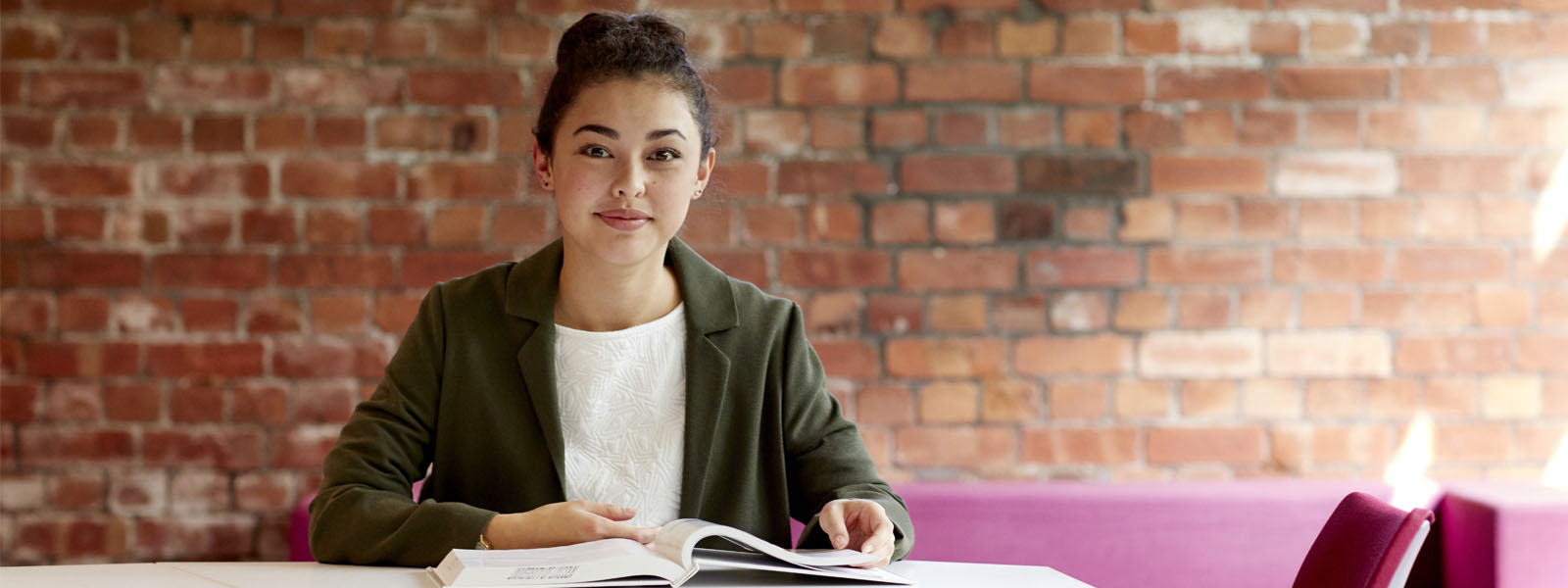 Girl smiling to camera with a book in the University's Great Central Warehouse Library