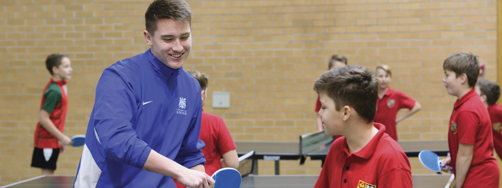 Sports teacher with children playing table tennis