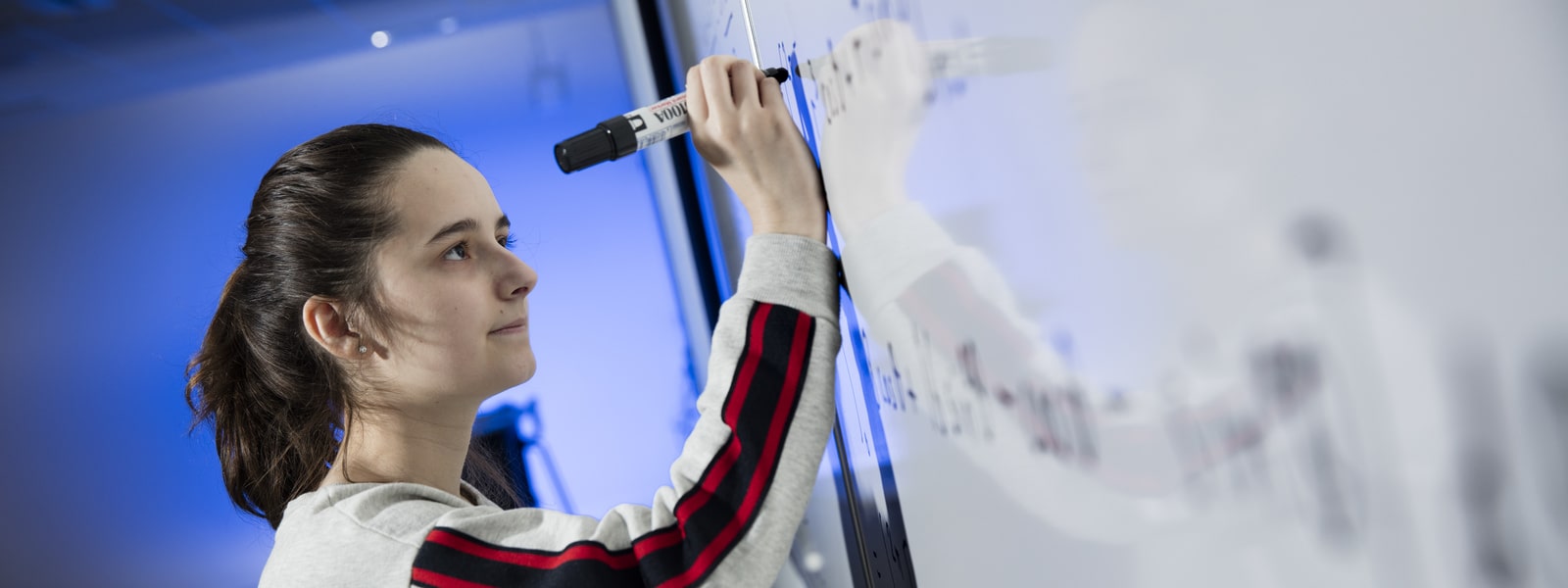 Student solving equations on a white board