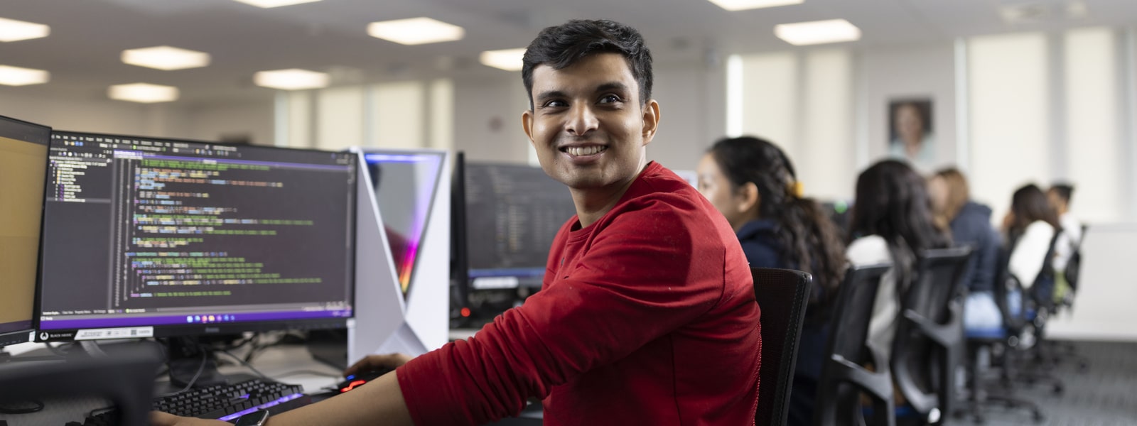 A student working at a computer with code on the screen