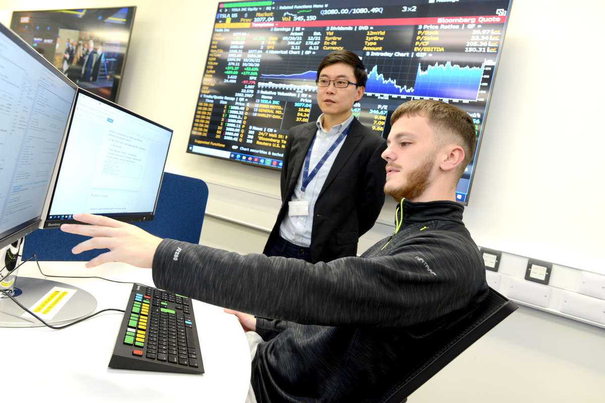 An academic working with a student in the Bloomberg Terminal lab.