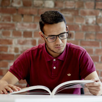Male student reading a book indoors