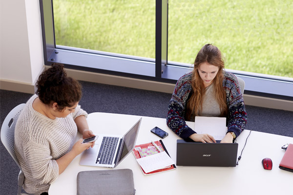 Two students sat working on laptops