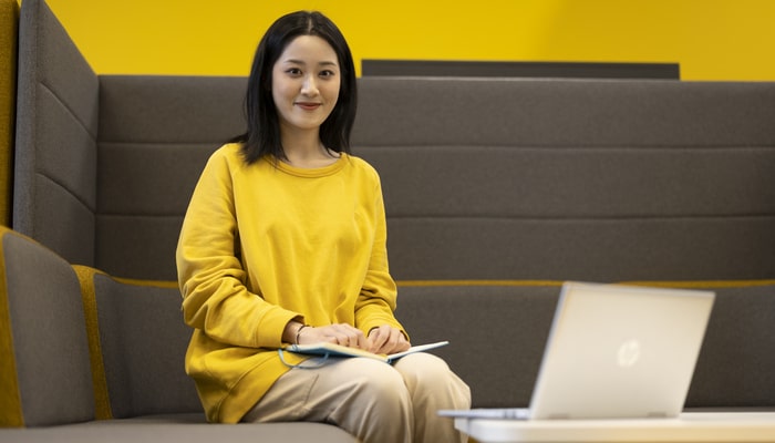 A student sit with a laptop and notepad