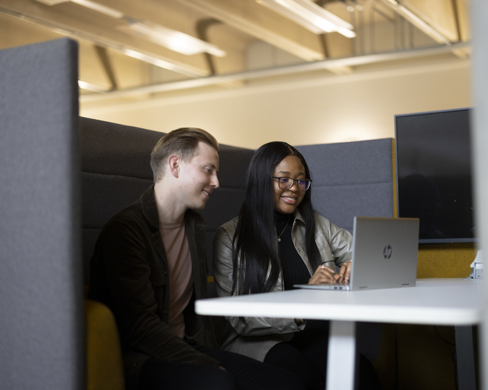 Two students sat at a desk with a laptop