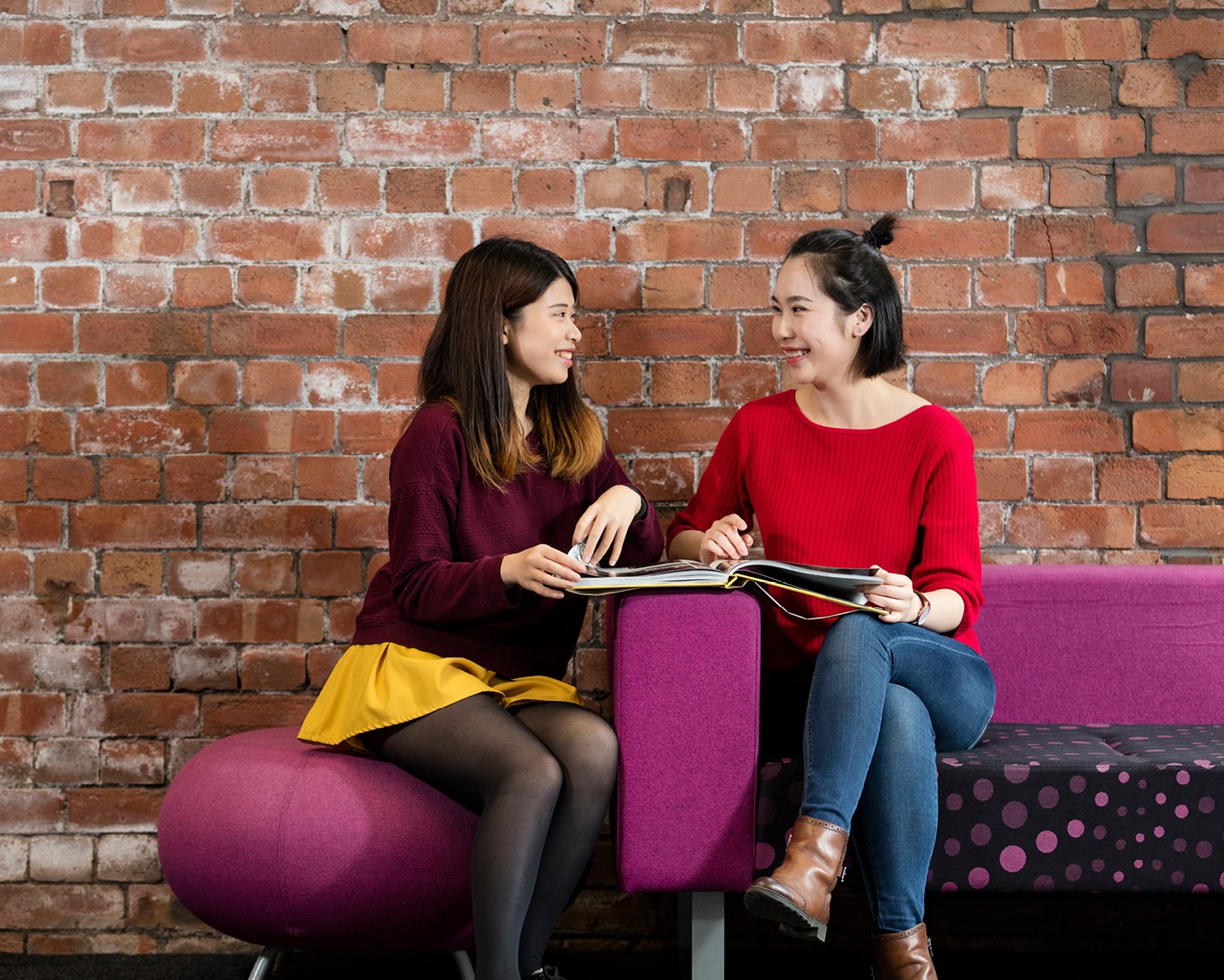 two students sitting on sofa talking to each other