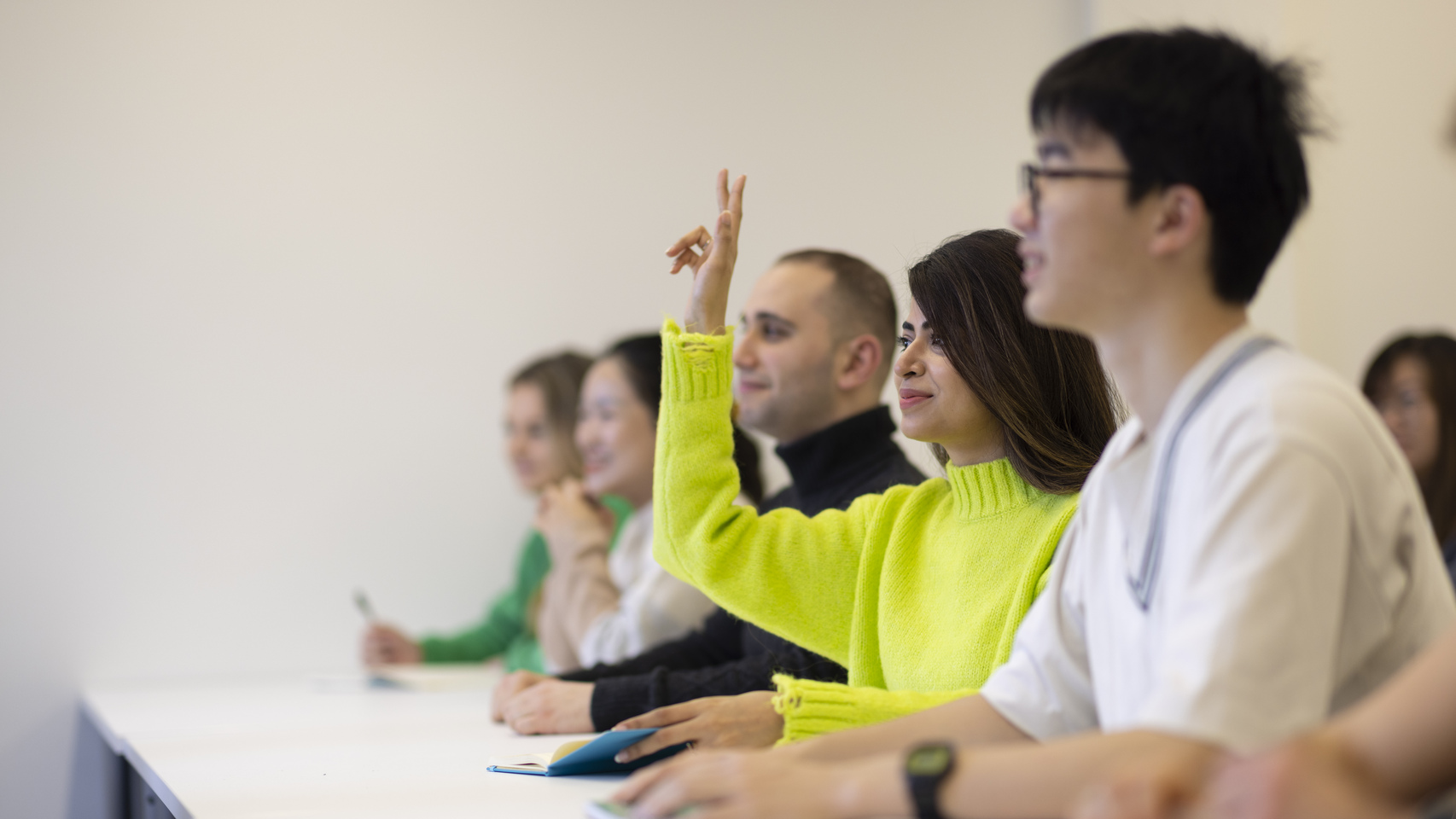 A student raises their hand at a desk