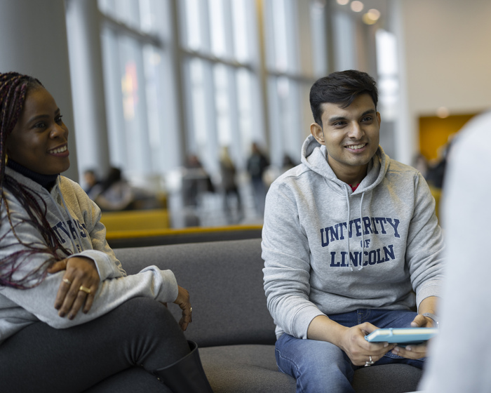 Students in Lincoln hoodies talk on a bench