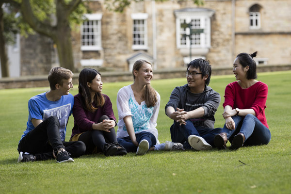 A group of students sitting on the grass and chatting