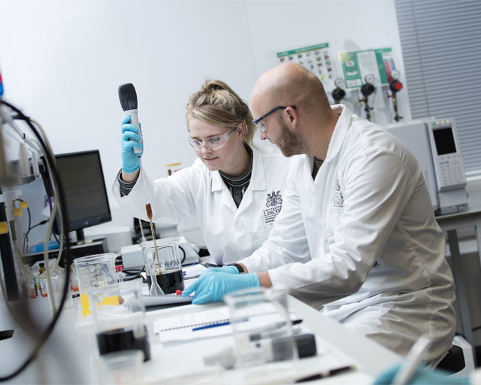 A member of staff working with a student in a science lab