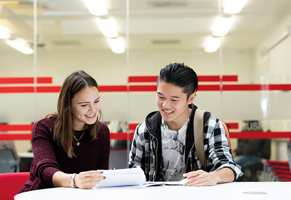 Two students sat at a desk reviewing a paper