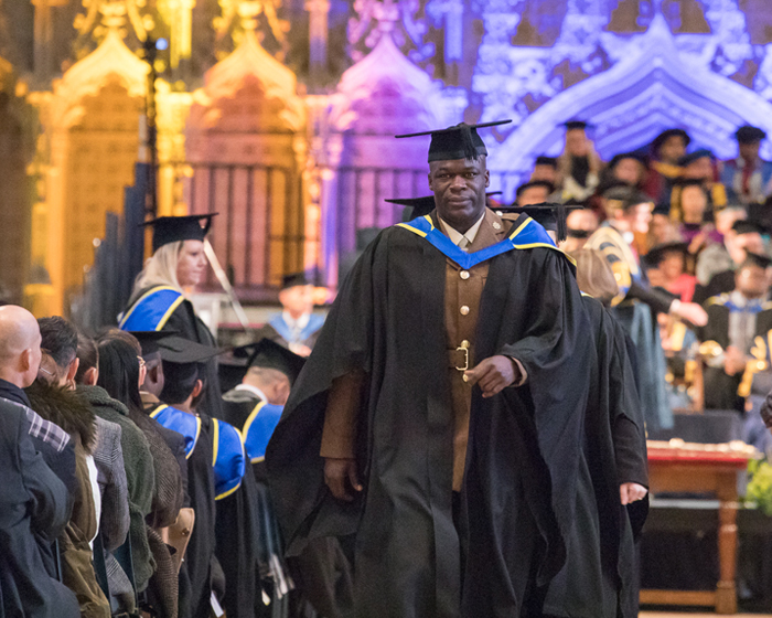 Student in gown and cap, walking down the aisle at a graduation ceremony in Lincoln cathedral