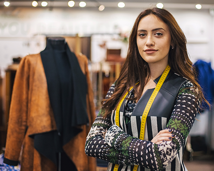 An apprenticeship fashion student stood in front of clothes on display in a shop