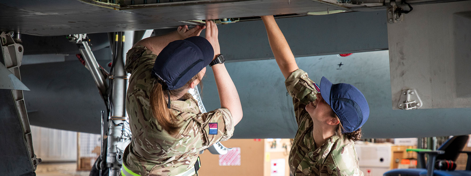 Two female soldiers inspecting the underside of an aeroplane