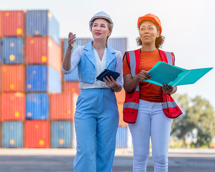 Women walking and talking in shipping container yard