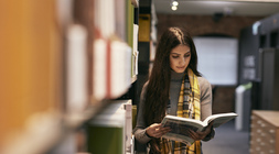 Student in the library, reading a book