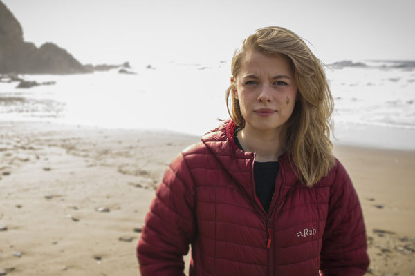 Woman in red coat standing on beach