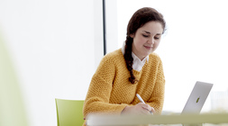 Student sitting down taking notes at a table