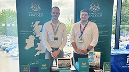 Staff standing at a Lincoln HE fair event stand.