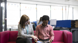 Student and staff member reading an academic book