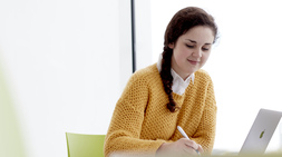 Student writing at a desk