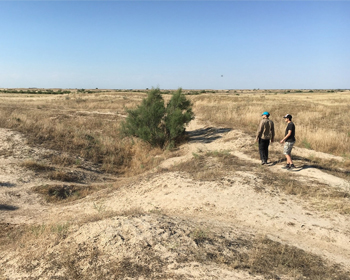 Two people standing near an abandoned medieval canal in the desert