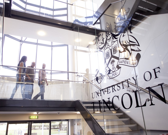 A group of academics walking on the landing in a University of Lincoln building