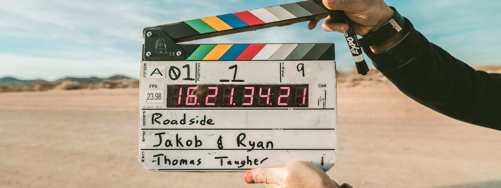 A pair of hands holding a film clapperboard