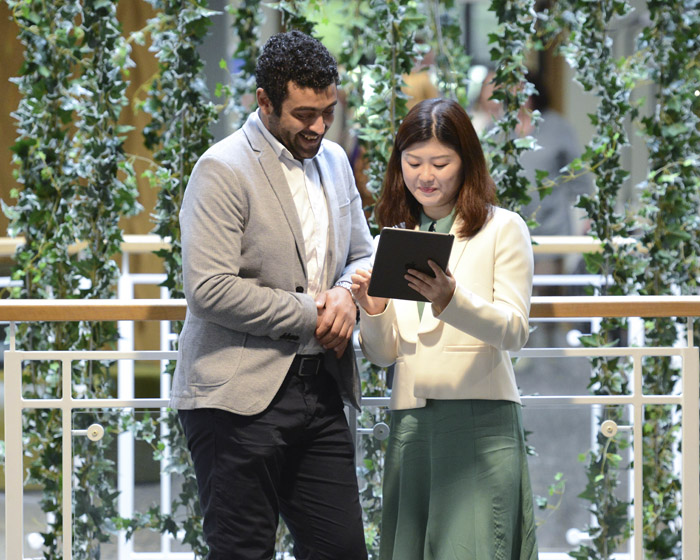 Two students stood with a tablet device