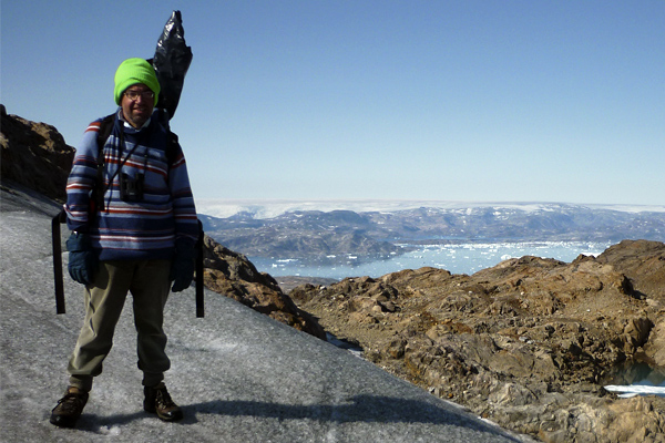 A man standing overlooking a glacier in Greenland