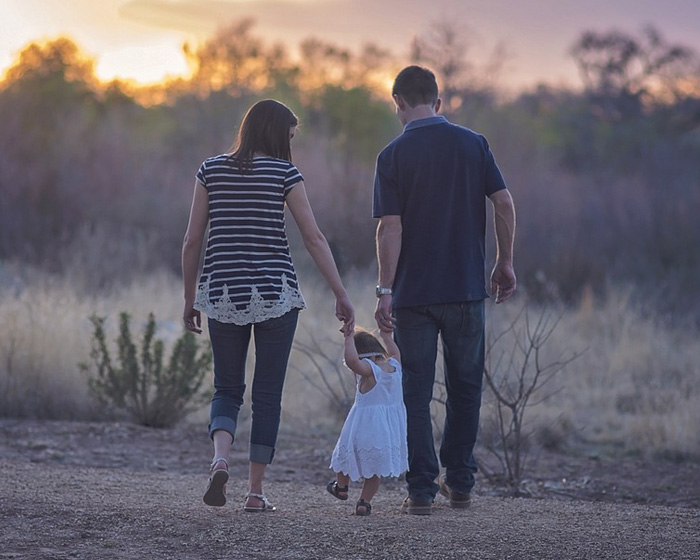 Two parents walking and holding hands with a child