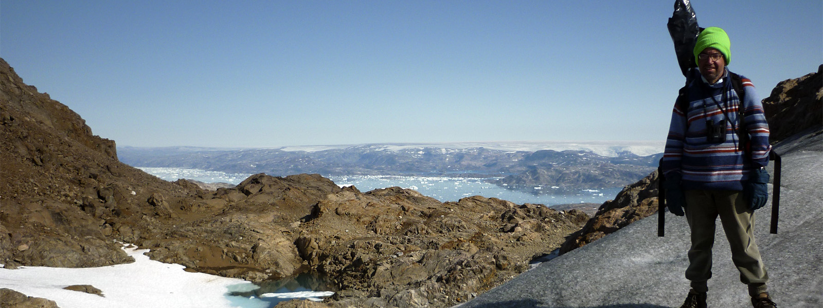 A man standing overlooking a glacier in Greenland