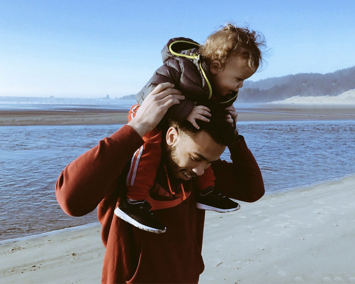 A father carrying his child and walking on the beach