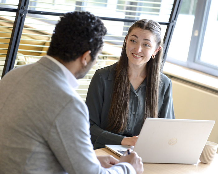 Two students working on a laptop in a study space