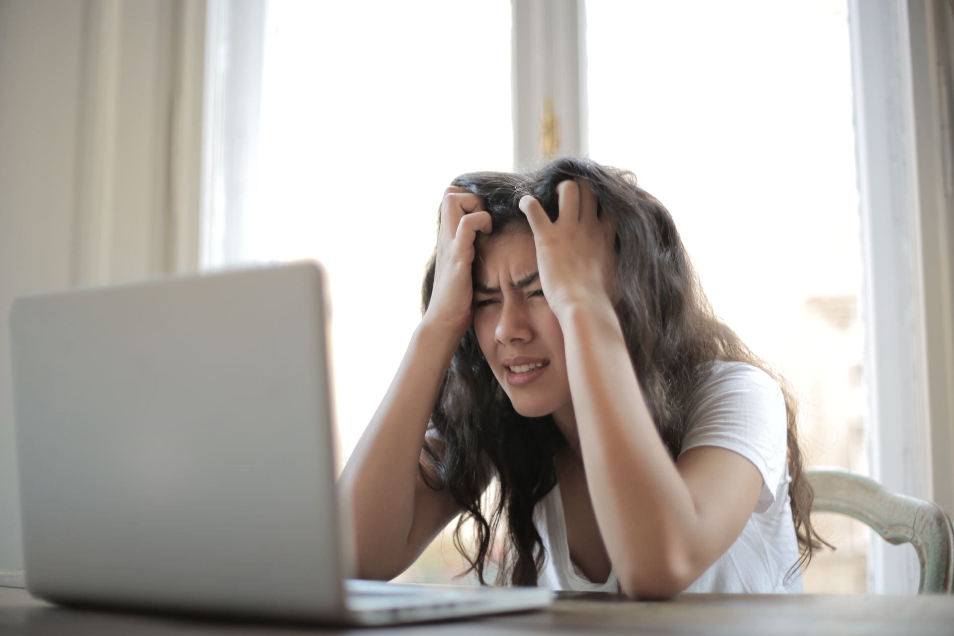 A woman holding her head in both hands looking anxious