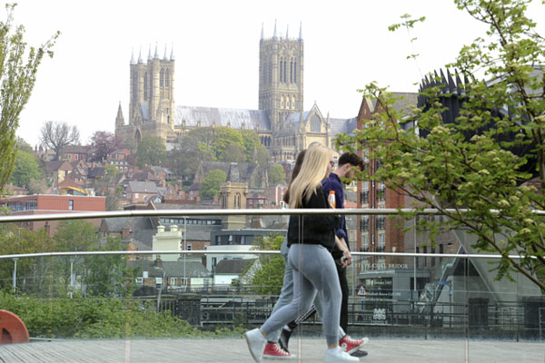 A group of students walking across a bridge into Lincoln city centre