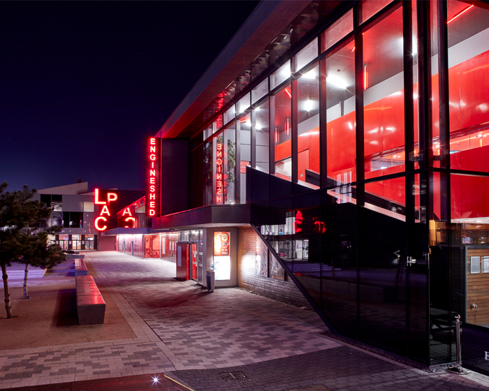 Exterior of the Engine Shed at night, with the Lincoln Arts Centre in the background