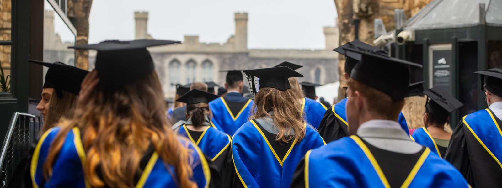 Graduates walking into Lincoln castle grounds in their gowns, hoods, and caps