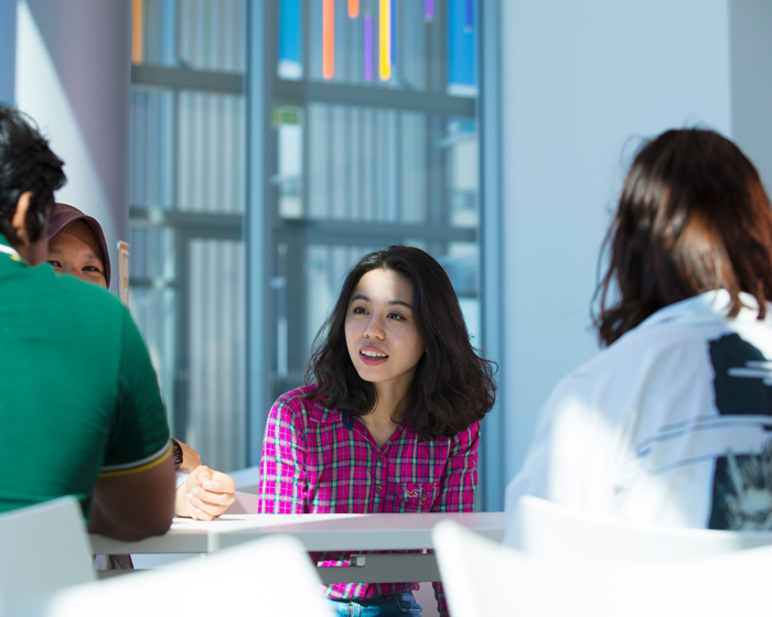 A group of students sat together at a table in the Isaac Newton Building atrium