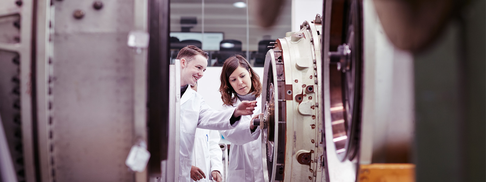A student in a lab coat looking at a test tube