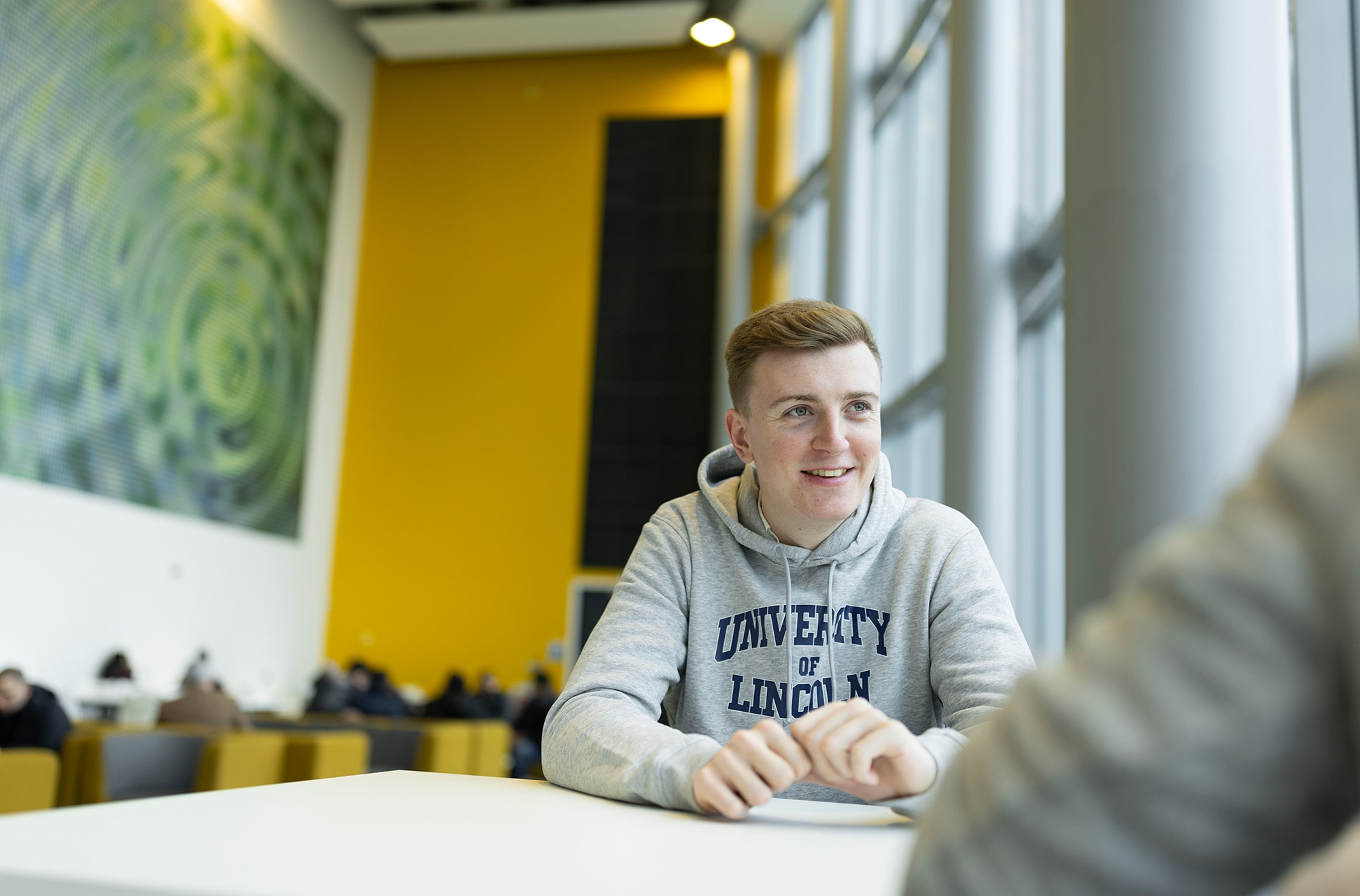 A male student sat in a University of Lincoln jumper