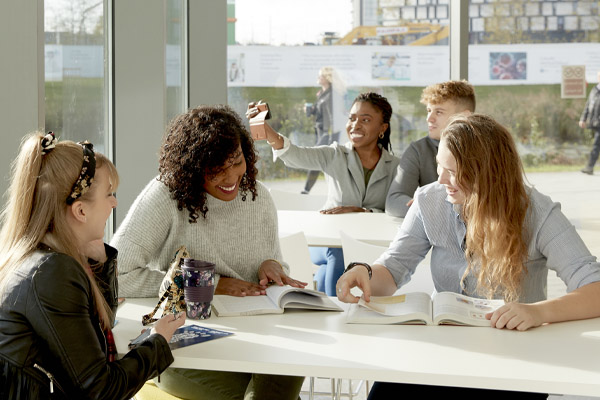 A student taking a selfie in a study room surrounded by other students