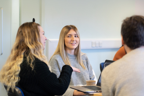 Student sat smiling as another talks